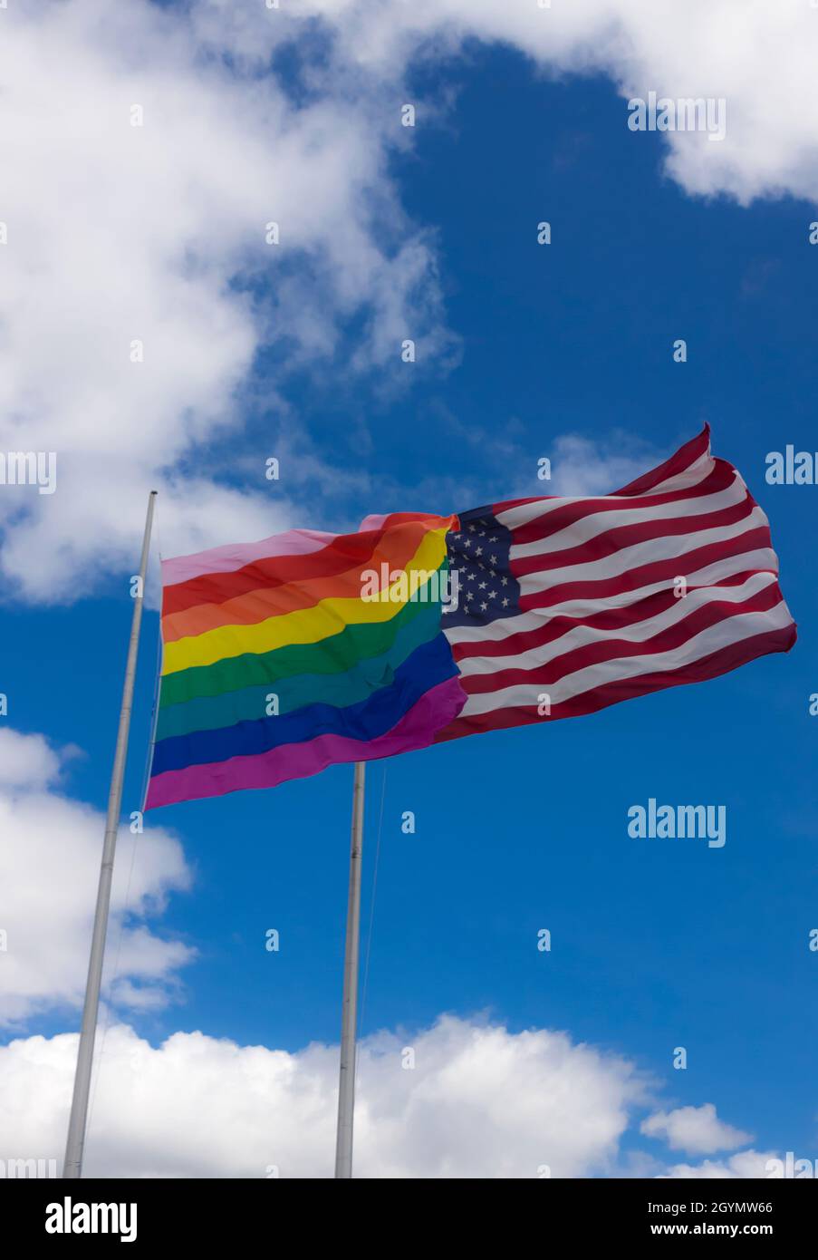 Bandera arco iris/bandera de orgullo gay (LGBT) volando junto a la bandera americana en Cherry Grove, Fire Island, Nueva York, Estados Unidos de América. Foto de stock