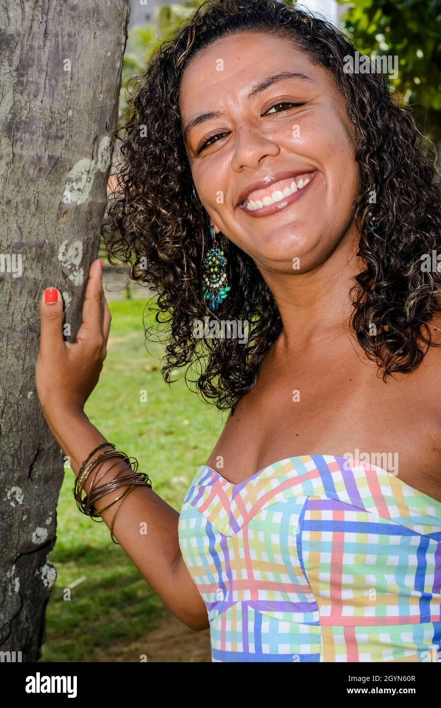 Retrato de modelo negro sonriendo junto a un árbol de coco mirando a la cámara. Concepto de alegría, madurez y conciencia negra. Salvador, Bahía, Brasil. Foto de stock