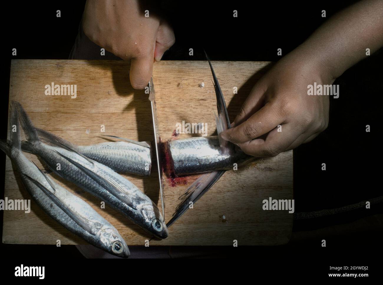 El pescado crudo se corta antes de cocinarse. Primer plano mano. Ángulo superior Foto de stock