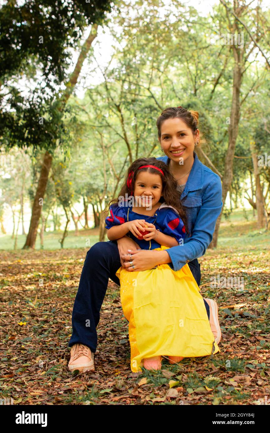 Una madre joven abrazando a su pequeña chica hispana usando un vestido de Blanca  Nieves como su traje de Halloween Fotografía de stock - Alamy