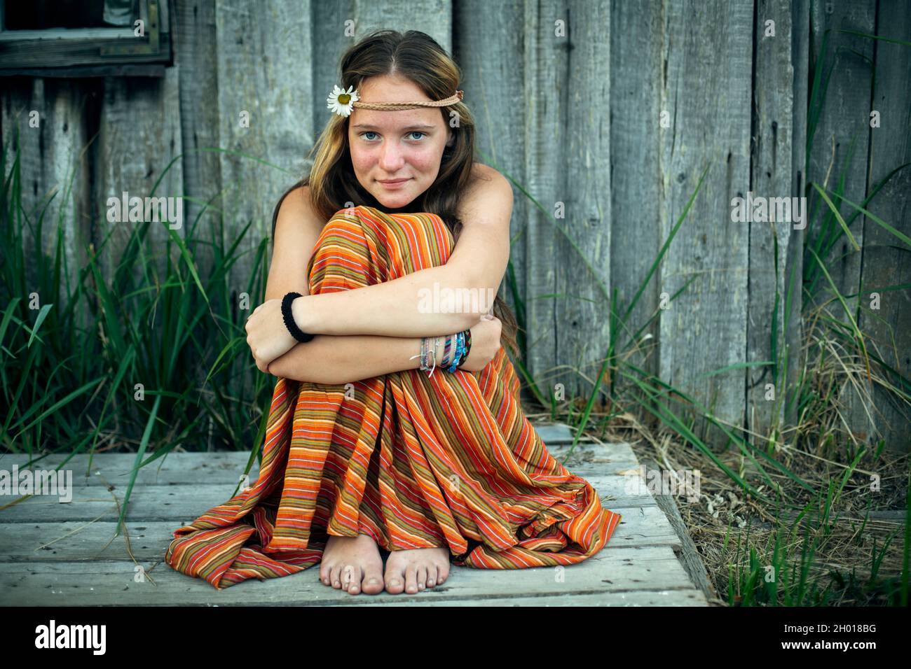 Una chica con ropa hippie sentada sola en el pueblo al aire libre