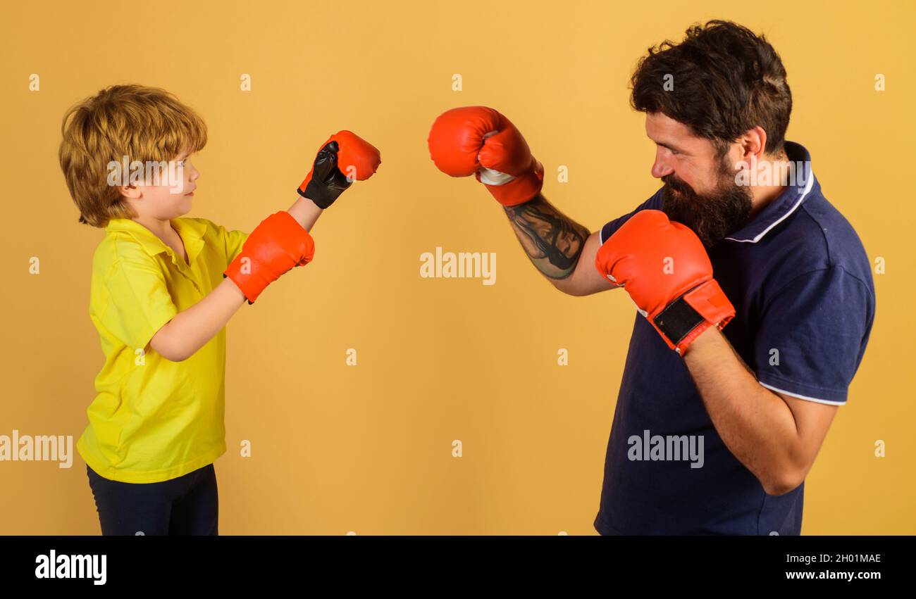Niño en entrenamiento de guantes de boxeo con entrenador. Golpe de gracia. Actividad infantil. El instructor enseña al niño cómo golpear los puñetazos. Foto de stock