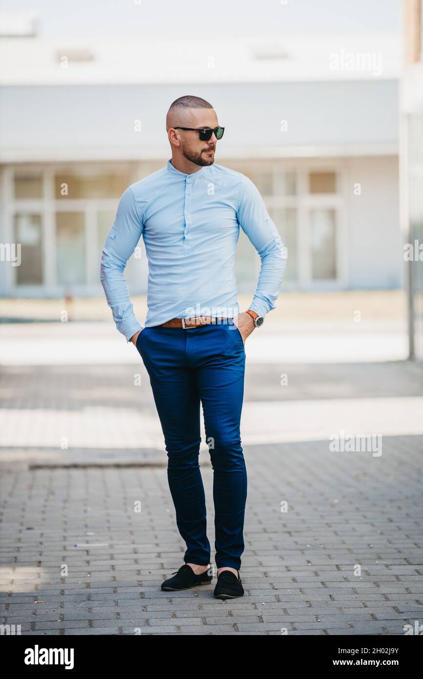 Hombre caucásico fresco guapo que lleva una elegante azul claro y gafas de sol posando al aire libre Fotografía de stock - Alamy