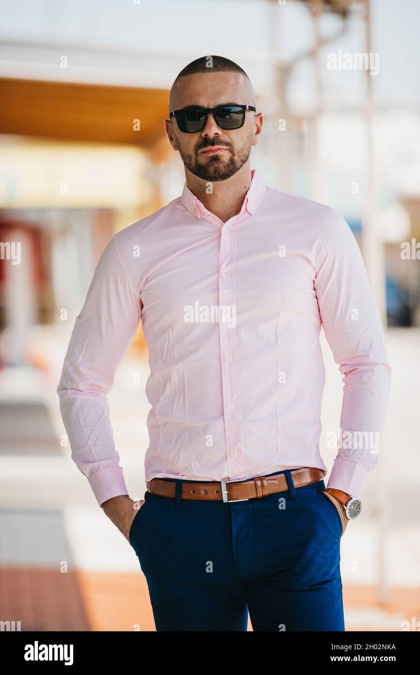 pacífico Especialmente moneda Hombre caucásico fresco guapo que lleva una elegante camisa rosa claro y  gafas de sol posando al aire libre Fotografía de stock - Alamy