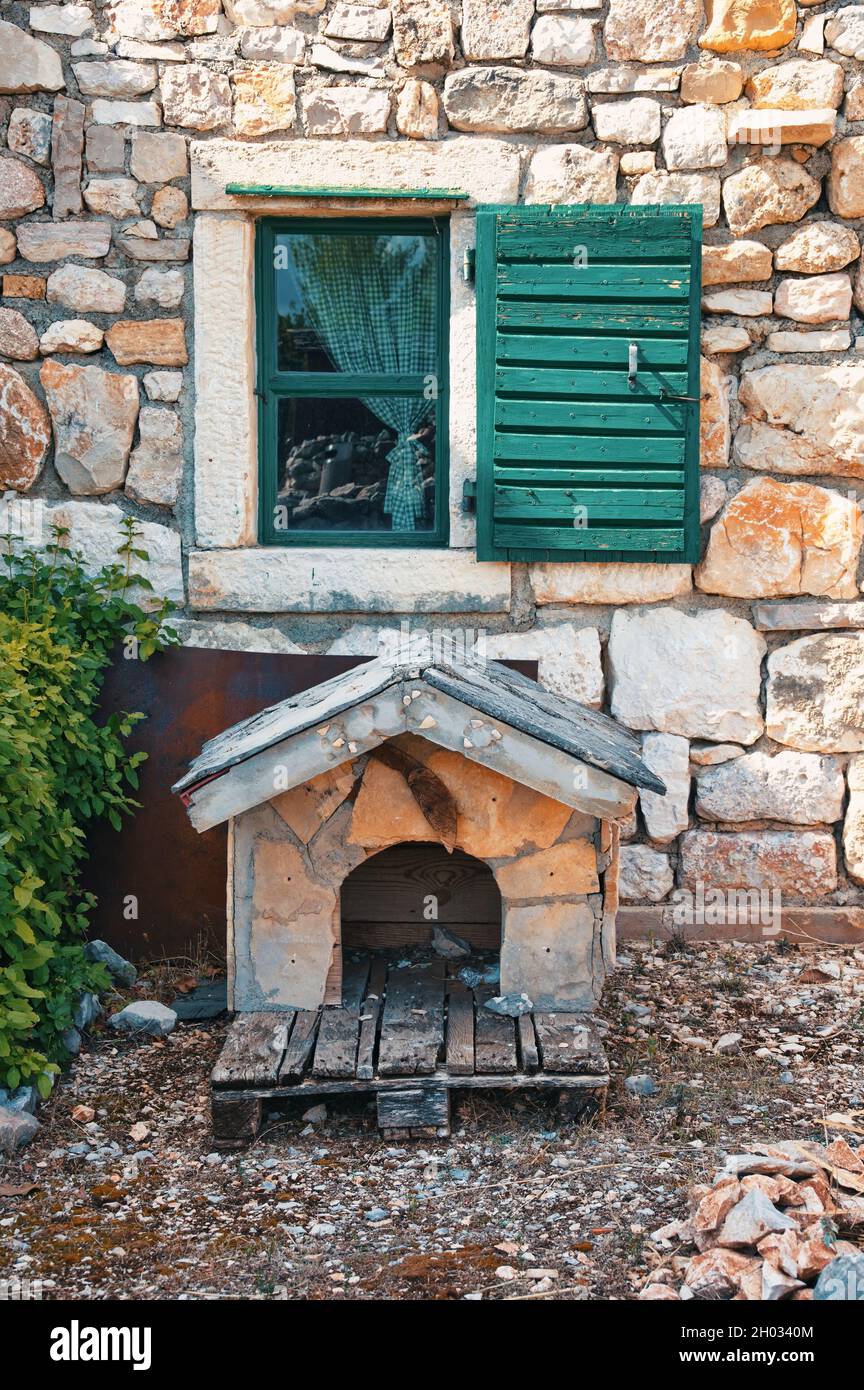 Casa para perros en frente de la casa mediterránea con ventana de madera  abierta y pared de piedra Fotografía de stock - Alamy