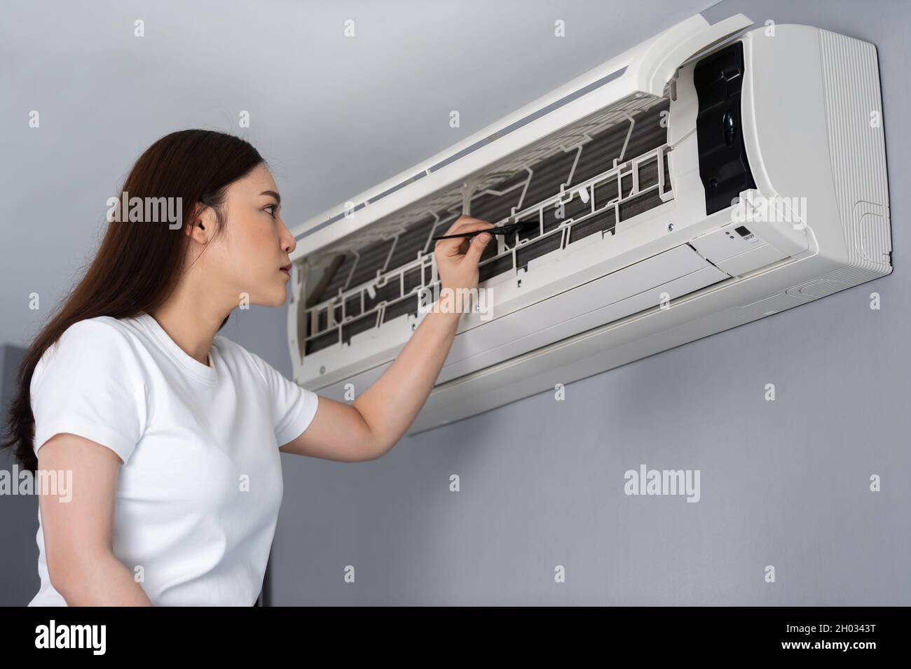 mujer joven usando un cepillo para limpiar el aire acondicionado en el  interior en el hone Fotografía de stock - Alamy