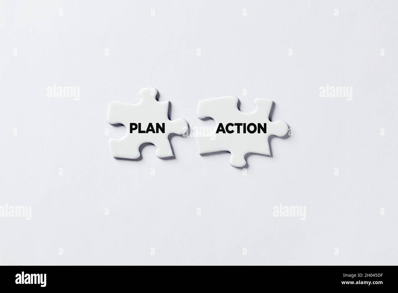 Dos piezas de rompecabezas de Jigsaw están conectando con el plan y la acción de las palabras. Tomar medidas y realizar el concepto de planes. Foto de stock
