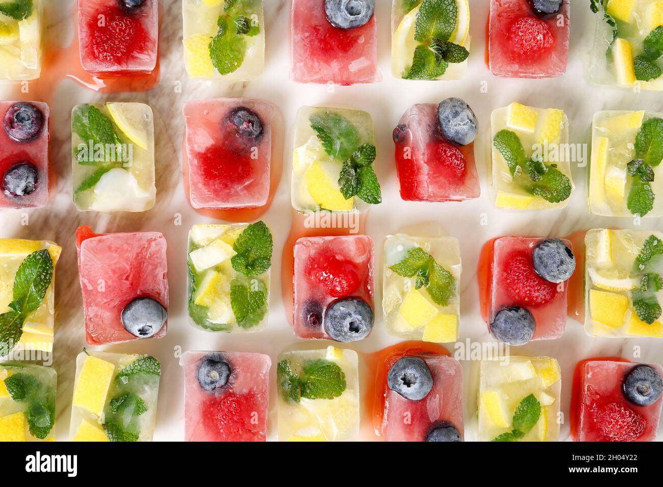Composición plana con cubitos de hielo de frutas y bayas sobre la mesa Foto de stock