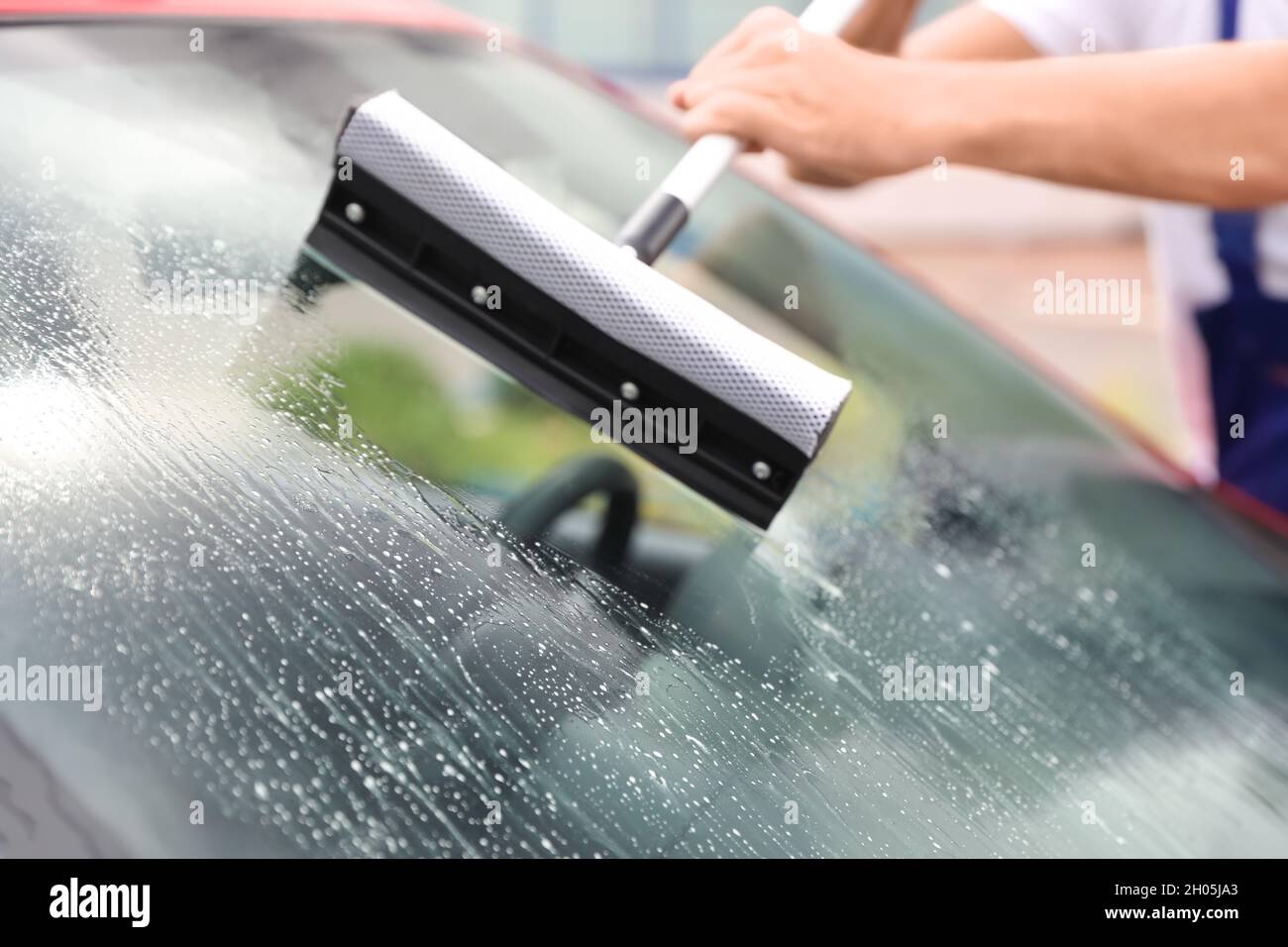 Hombre limpiando parabrisas con limpiacristales, primer plano. Servicio de  lavado de coches Fotografía de stock - Alamy
