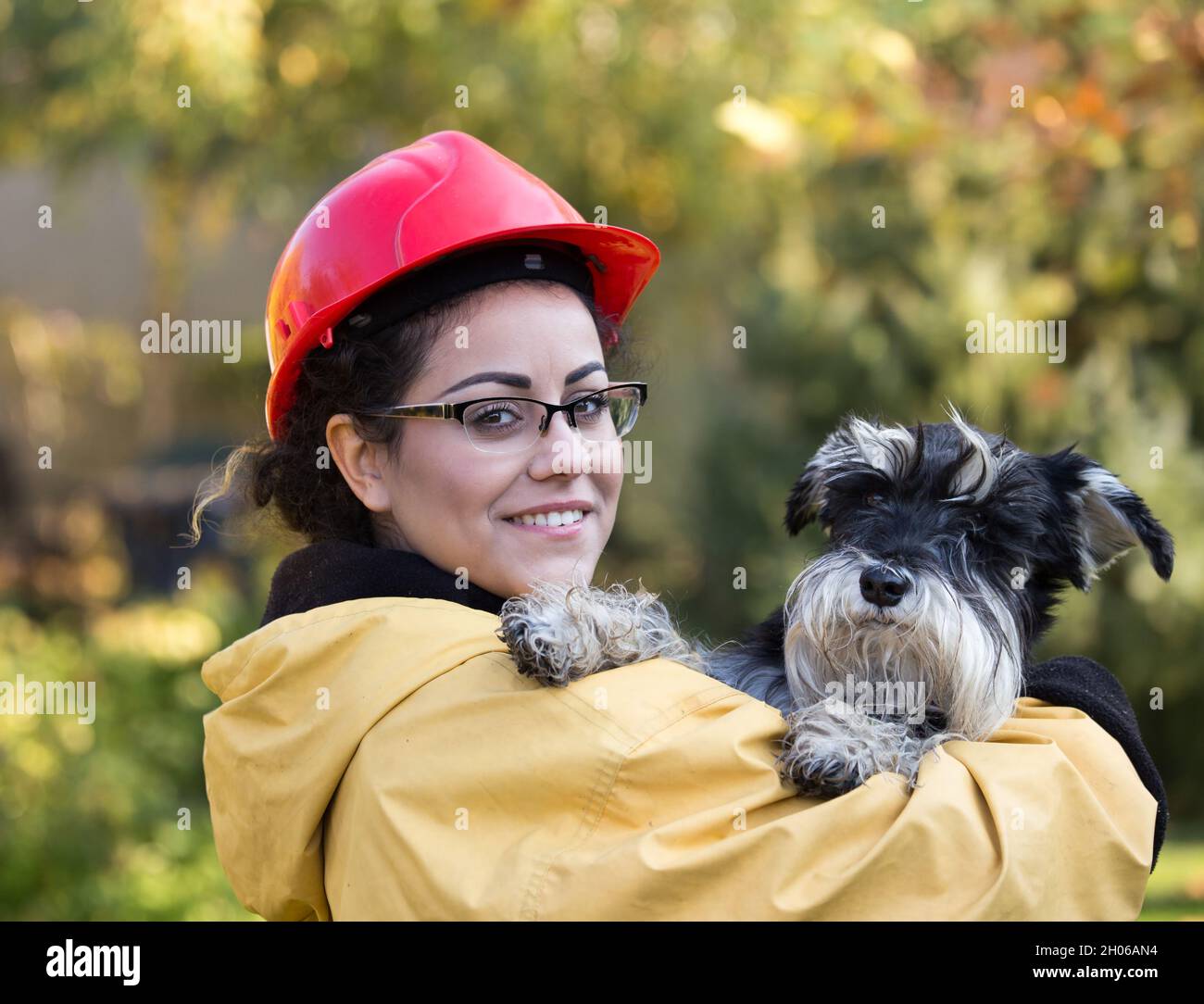 Mujer joven con chubasquero y casco con perro. Concepto de rescate de animales Foto de stock