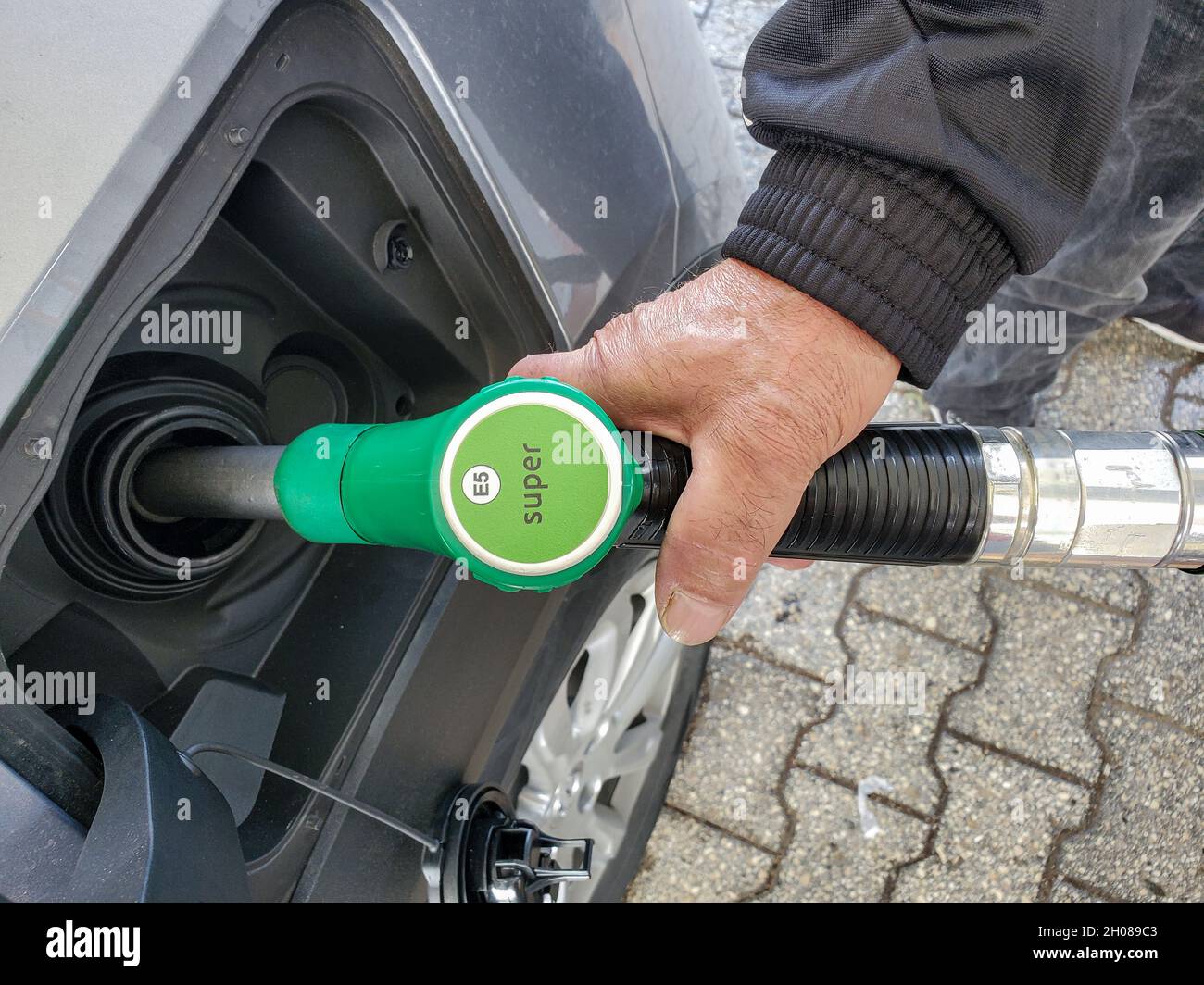 Hombre en gasolinera mientras se recarga un coche, concepto de aumento de los costes de gasolina Foto de stock