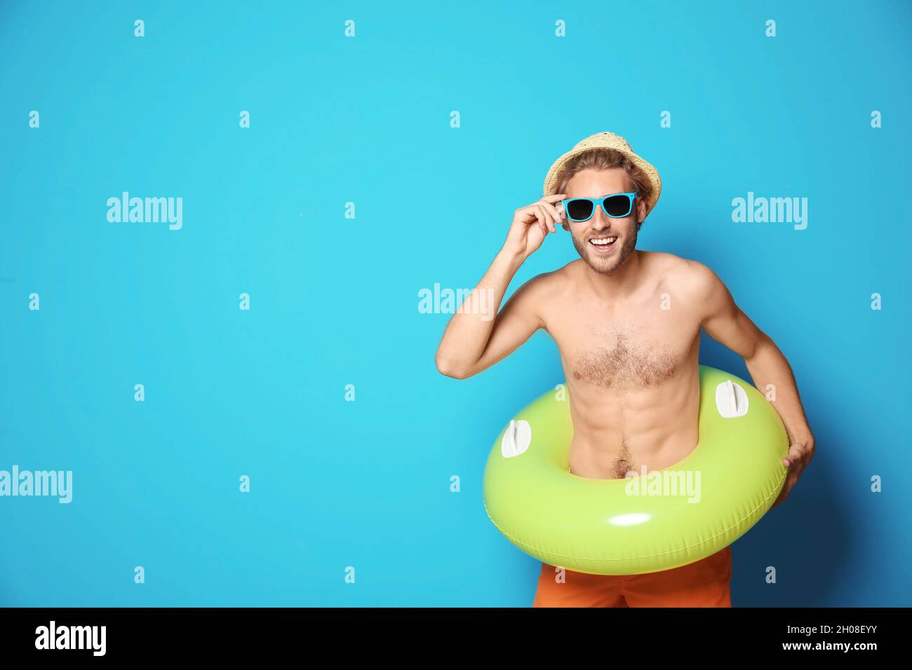 Hombre joven en pantalones cortos con anillo inflable contra fondo de  color. Espacio para texto Fotografía de stock - Alamy