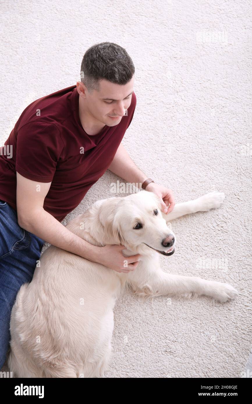 Hombre guapo con perro tumbado en la alfombra en casa Fotografía de stock -  Alamy