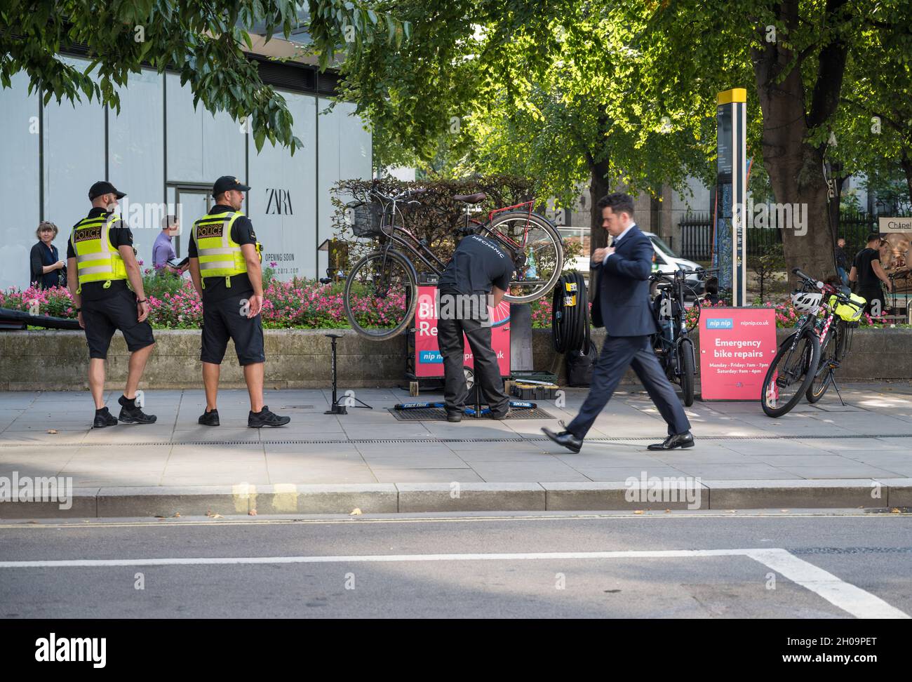 Mecánico trabajando en una bicicleta en un puesto de reparación de bicicletas de la policía de la ciudad de Londres en Cheapside, Londres, Inglaterra, Reino Unido Foto de stock