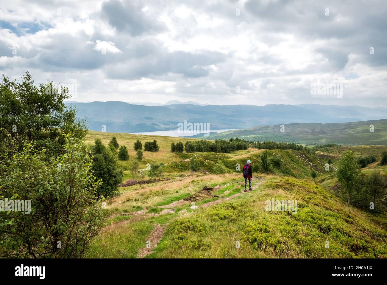 Mujer caminando por el paisaje escocés en un sendero cerca de Killin por encima del lago Tay Foto de stock
