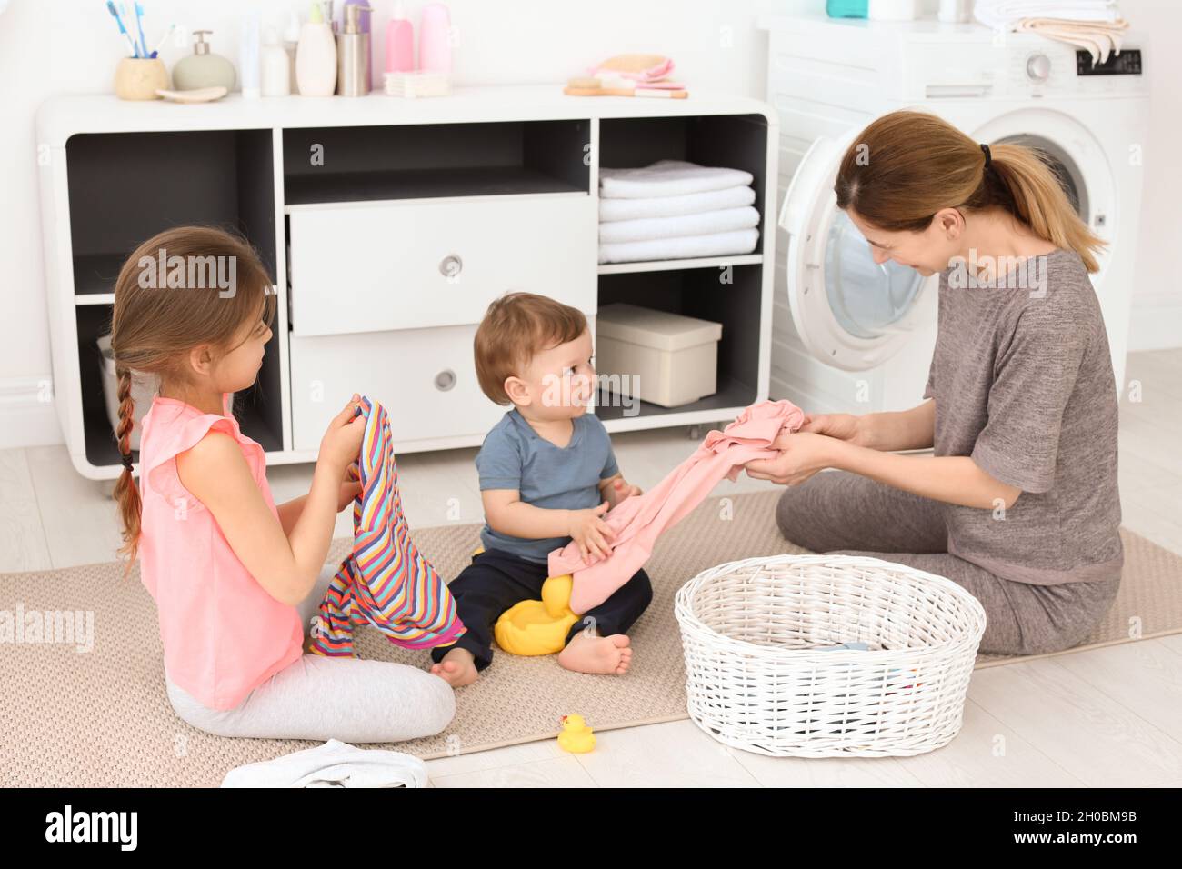 Ama de casa con niños doblando ropa recién lavada en la lavandería  Fotografía de stock - Alamy