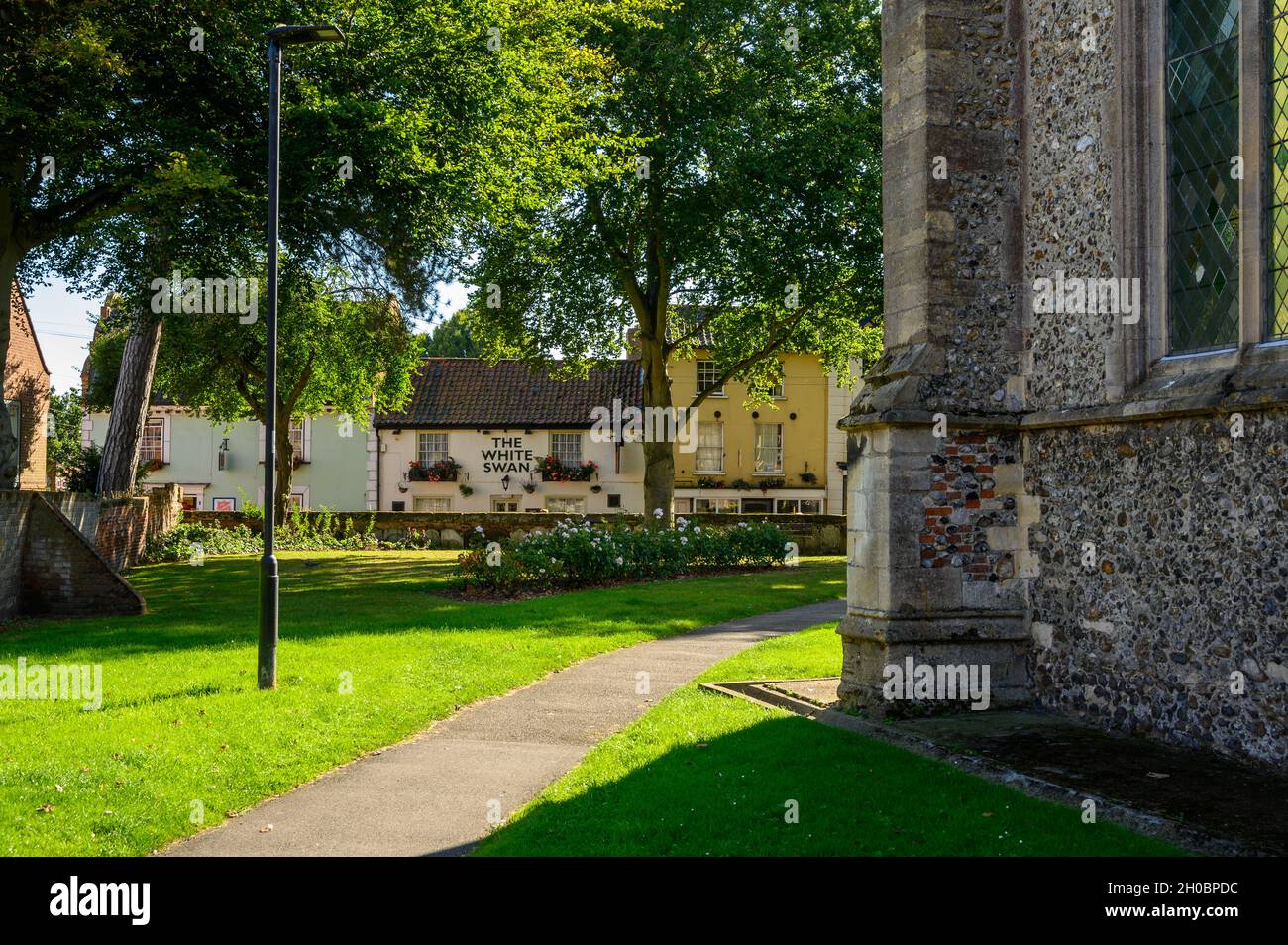 Vea la iglesia de San Nicolás y el cementerio hasta Church Street con el pub White Swan y la casa del Ejército de Salvación en North Walsham, Norfolk, Inglaterra. Foto de stock