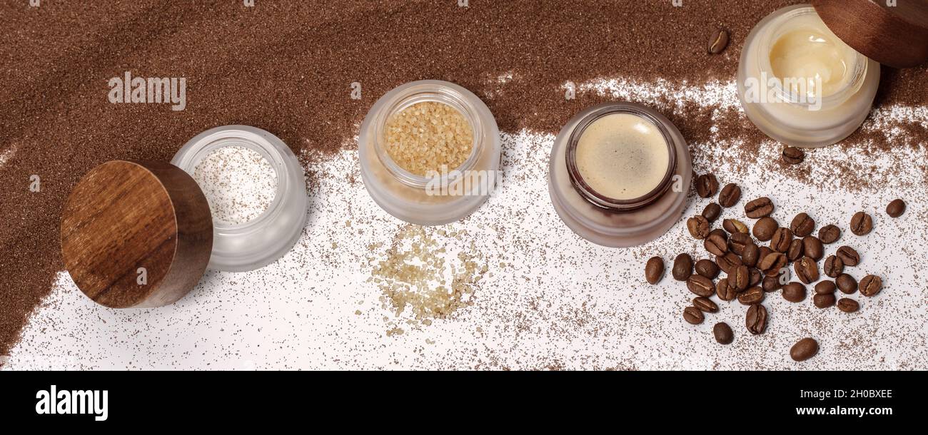 Azúcar moreno, café e ingredientes de miel para fregar en tarros de vidrio  con tapa de madera para cosméticos caseros sobre fondo de arena marrón.  Belleza, Spa, piel ca Fotografía de stock -