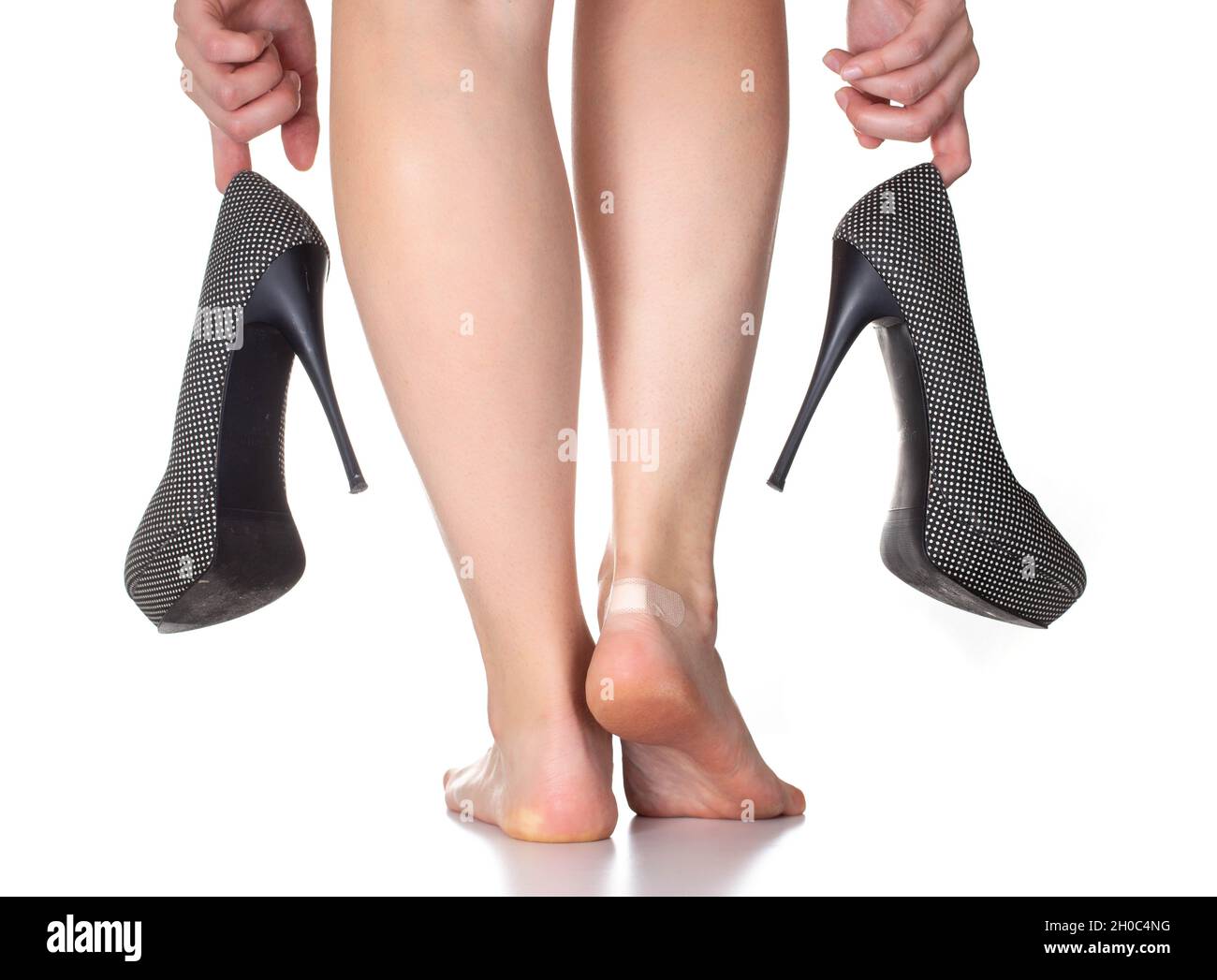 Chica sosteniendo zapatos de tacón alto sobre un fondo blanco. El concepto  de zapatos incómodos y callos de frotamiento Fotografía de stock - Alamy