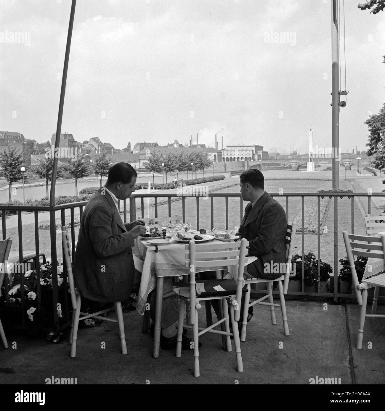 Zwei Männer in der Außengastronomie sitzen auf einer Terrasse en Mülheim an der Ruhr, Alemania 1930er Jahre. Dos hombres con catering al aire libre en una terraza de un restaurante en Muelheim, Alemania 1930. Foto de stock