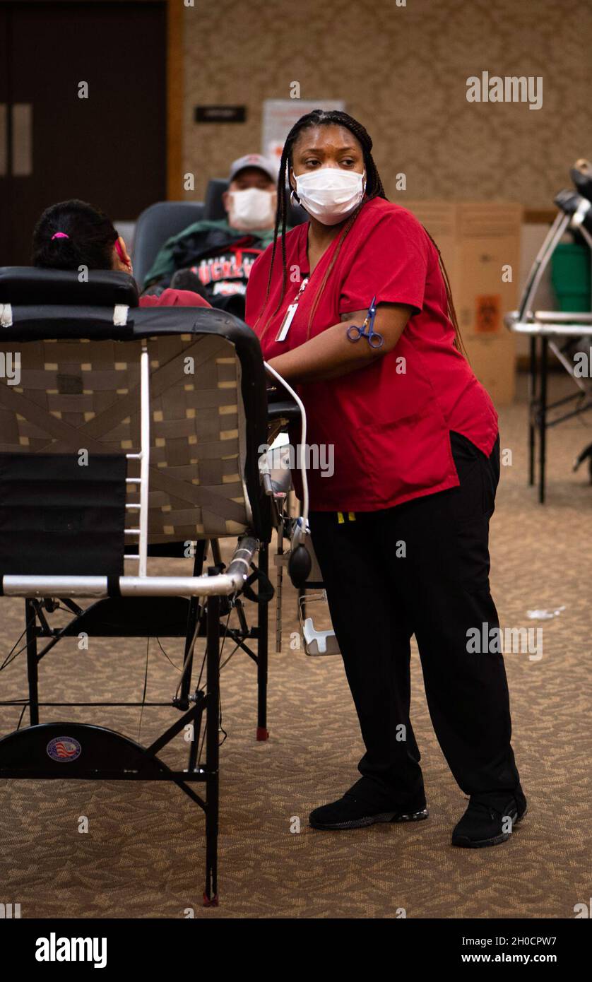 Williette Simmons, una voluntaria de la Cruz Roja Americana, ayuda a un donante a dar sangre durante una unidad comunitaria de sangre en el Club NCO el 25 de enero. Foto de stock