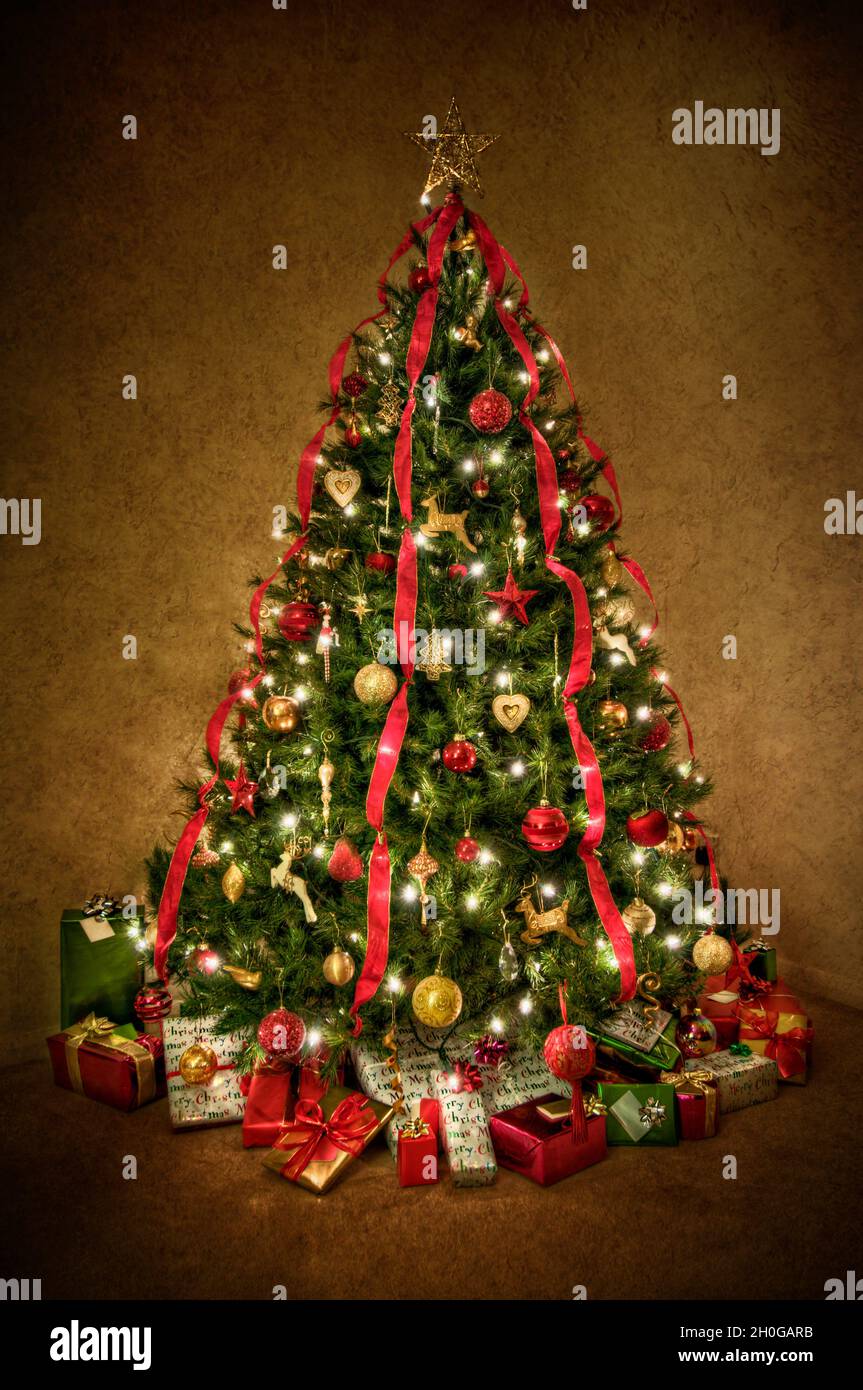 Consejo firma Llave Precioso árbol de Navidad decorado en rojo tradicional y dorado con cinta  roja que baja. Procesado para dar un efecto ligeramente surrealista y  brillante Fotografía de stock - Alamy
