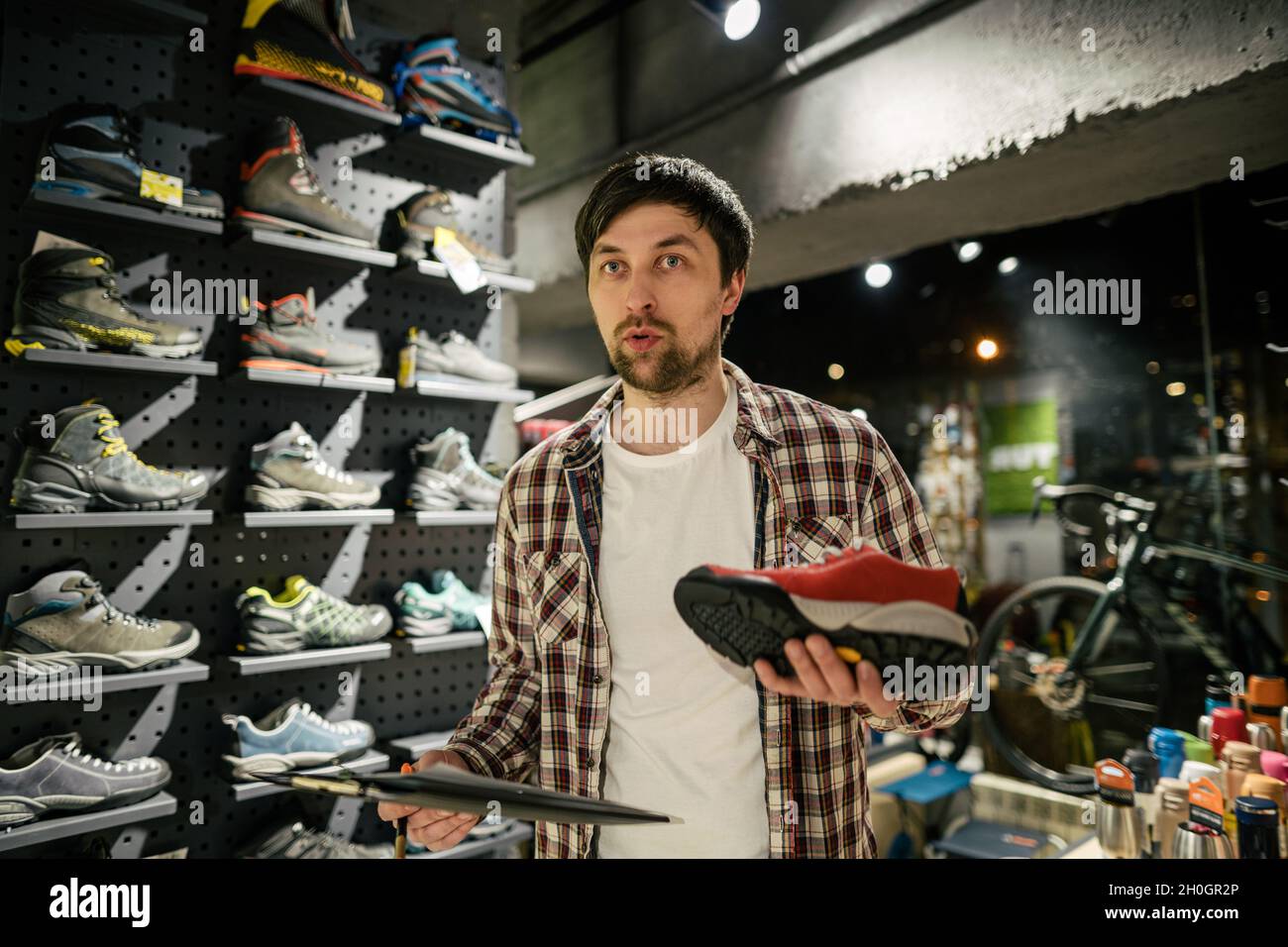 El vendedor aconseja al cliente sobre la elección de zapatos para caminatas  en una tienda al aire libre. Propietario de la tienda de turismo masculino  que ayuda al cliente a probar botas