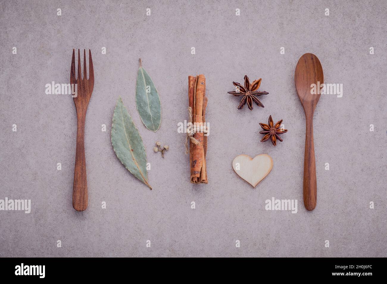 Cuchara de madera ,horquilla ,canela ,anís estrella ,corazón de madera y  hojas de laurel en concepto de papel cartón marrón de dulces y menú del día  de San Valentín Fotografía de stock -