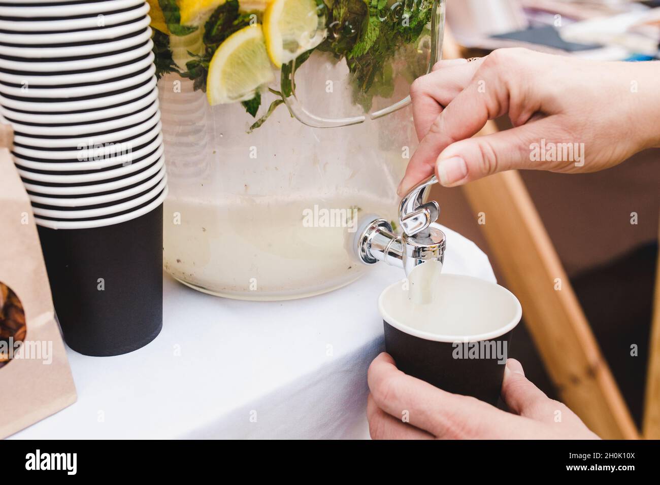 Jarra de cristal con dispensador y refresco de limón en el interior - una  chica se vierte un vaso Fotografía de stock - Alamy