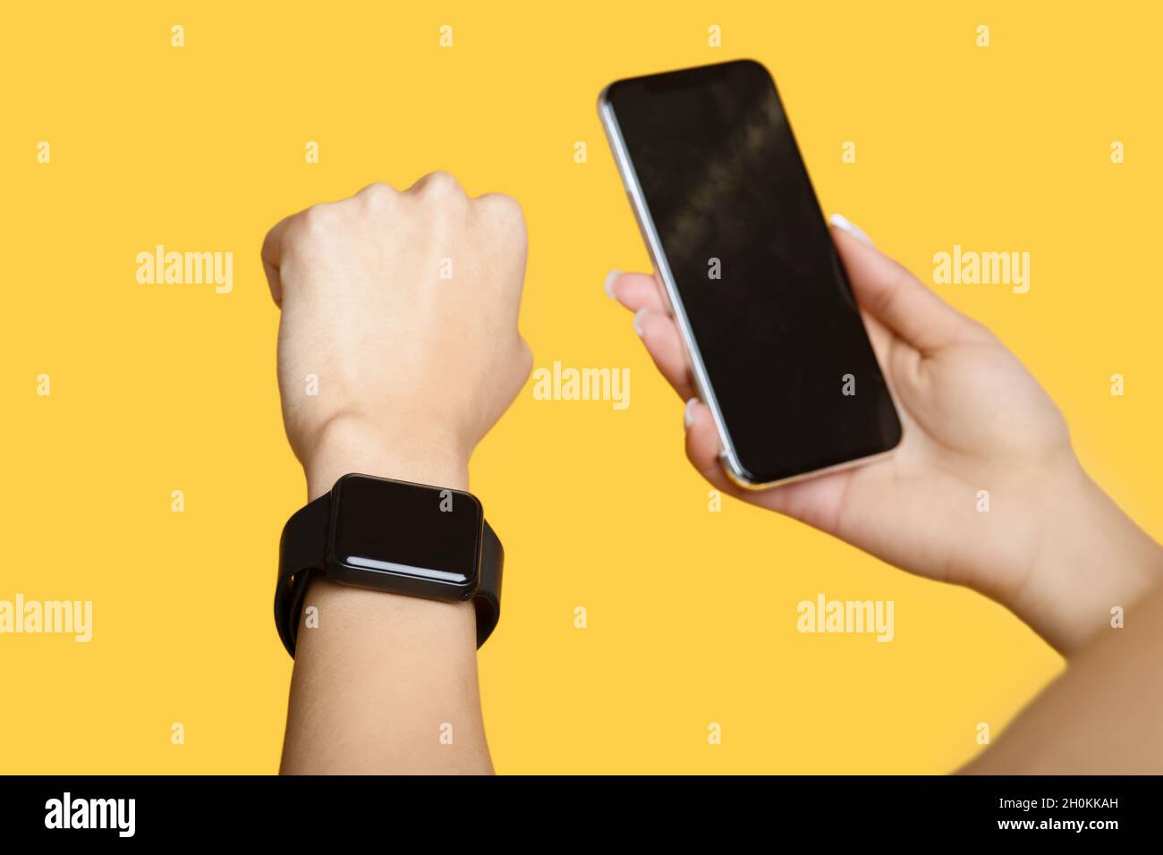 Dispositivos para el deporte. Mujer joven con reloj inteligente y smartphone  con pantalla negra en blanco y fondo amarillo Fotografía de stock - Alamy
