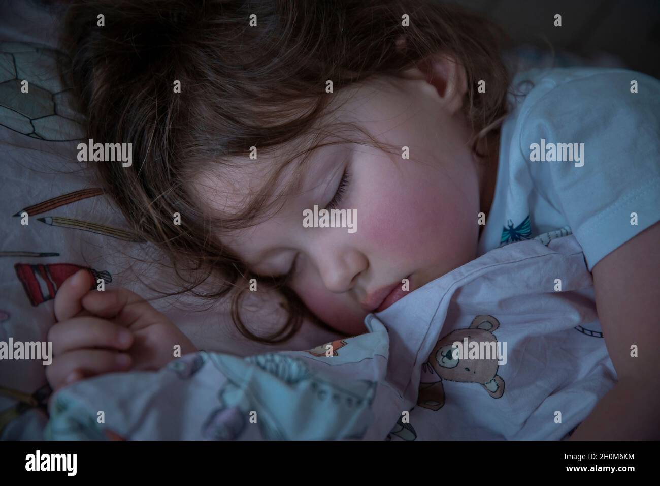 Linda niña de 3 años durmiendo en su cama Foto de stock