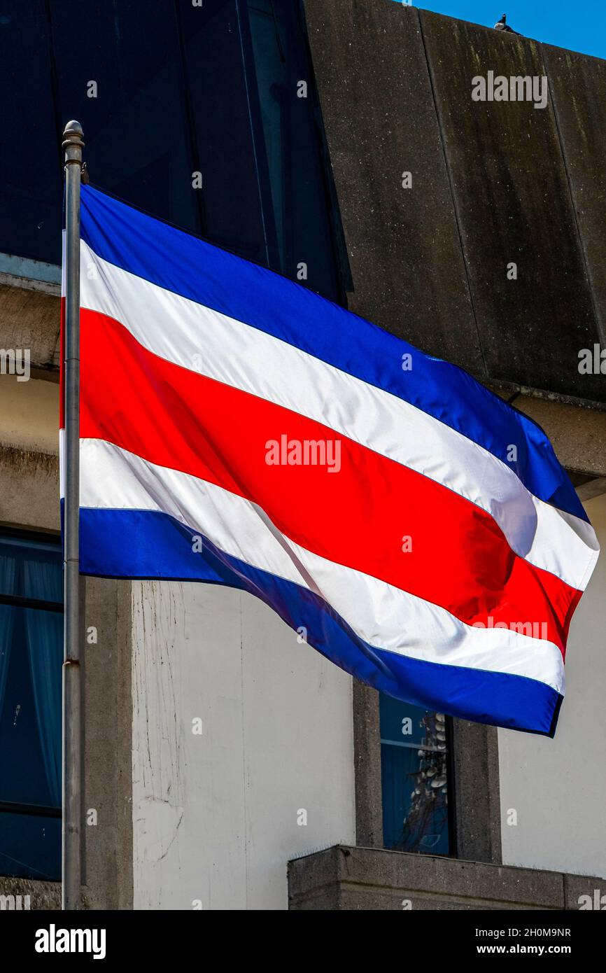 Bandera de Costa Rica con edificios antiguos detrás de bandera de Costa Rica azul blanco criado en San José Costa Rica. Foto de stock