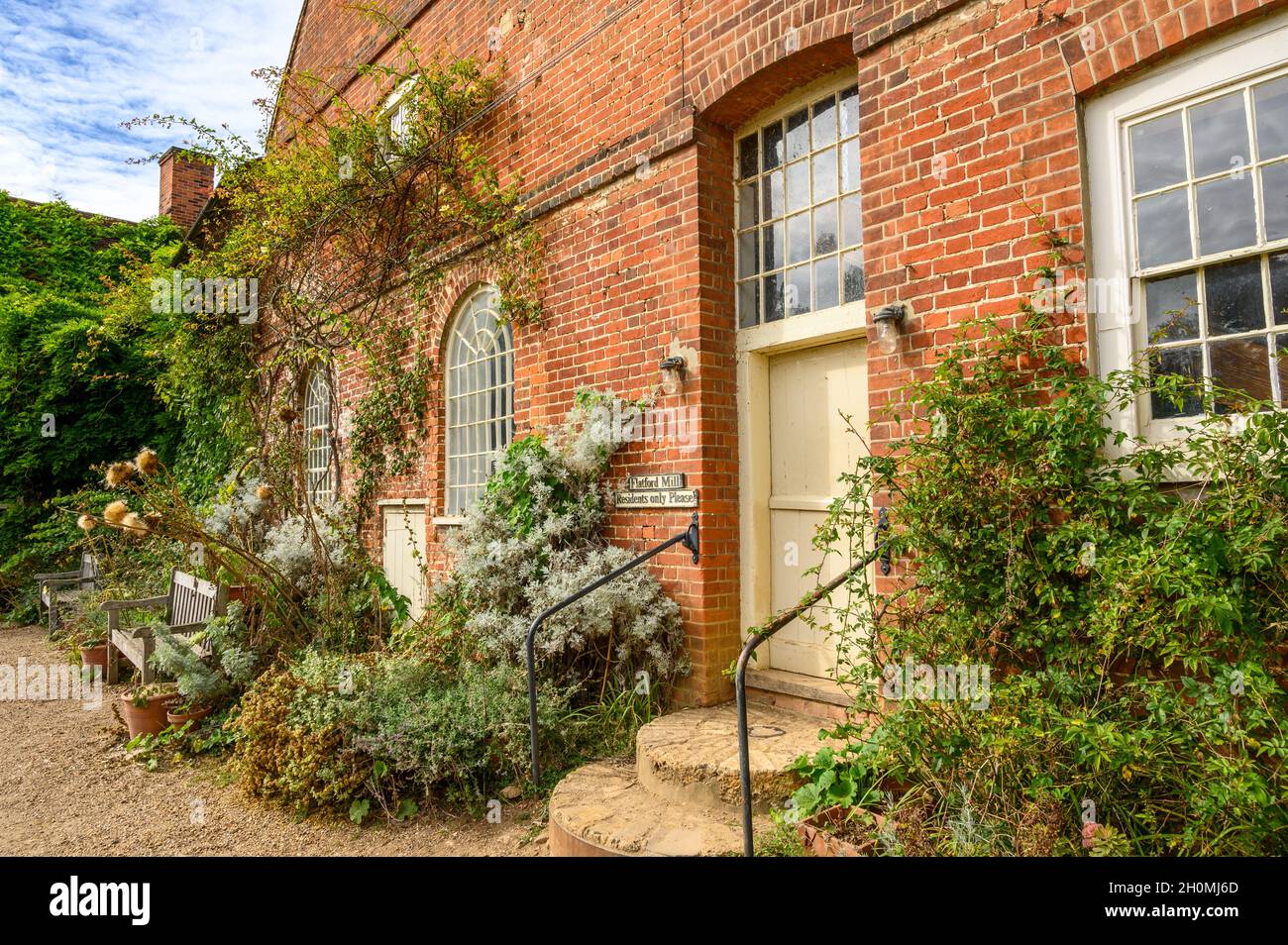 Fachada de ladrillo rojo del histórico Flatford Mill con plantas de escalada y bancos en Flatford, Suffolk, Inglaterra. Foto de stock