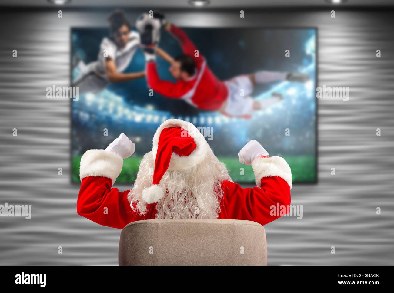 Alegre Santa Claus, fan del fútbol, mira un juego en la televisión Foto de stock