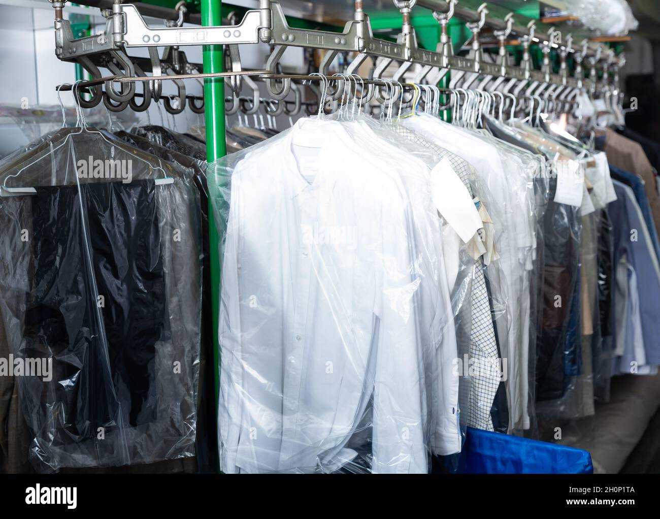 Limpie la ropa empacada colgada en las perchas en la lavandería Fotografía  de stock - Alamy