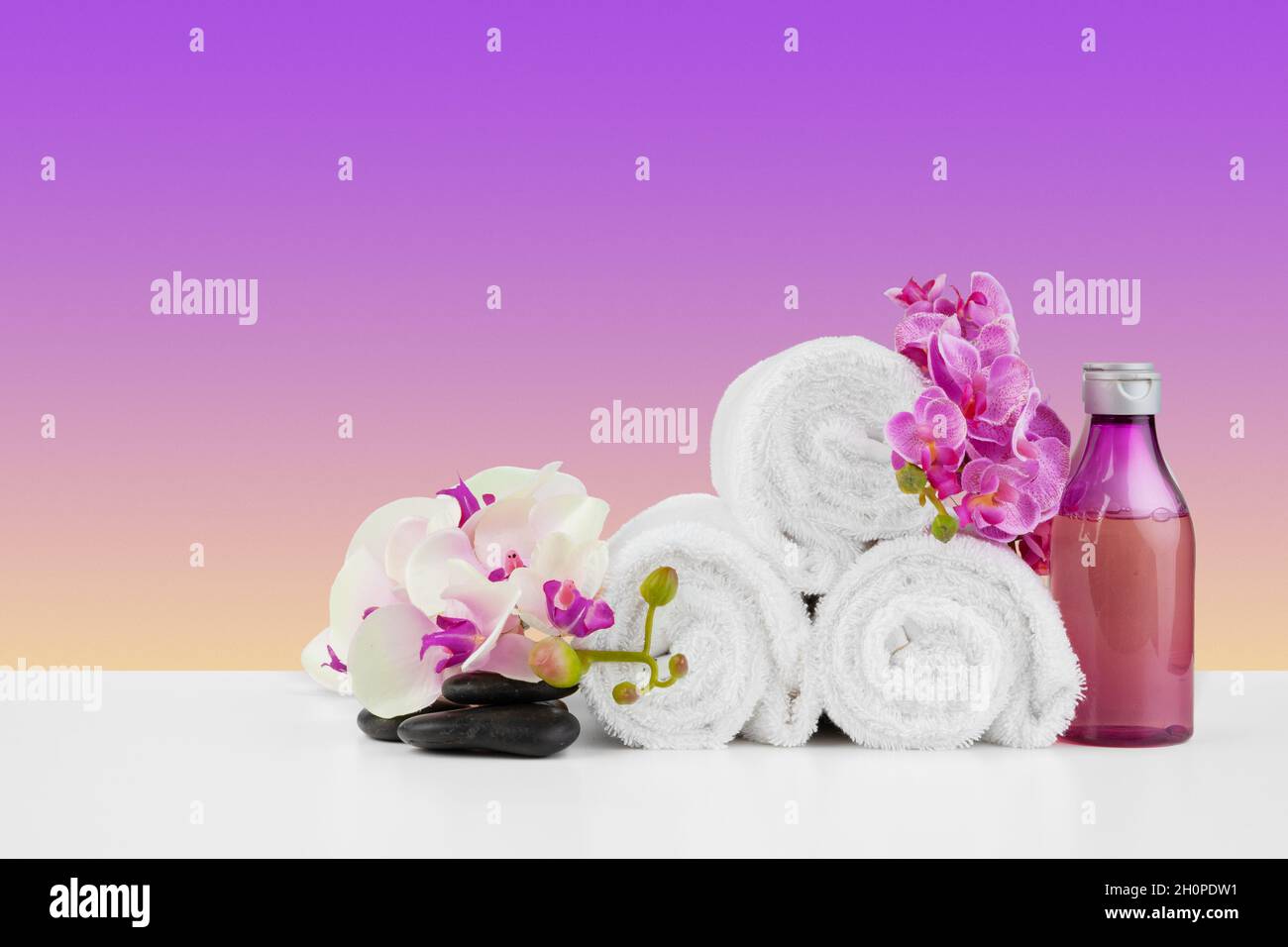 Hermosas flores rosadas y toallas blancas sobre fondo rosa Foto de stock