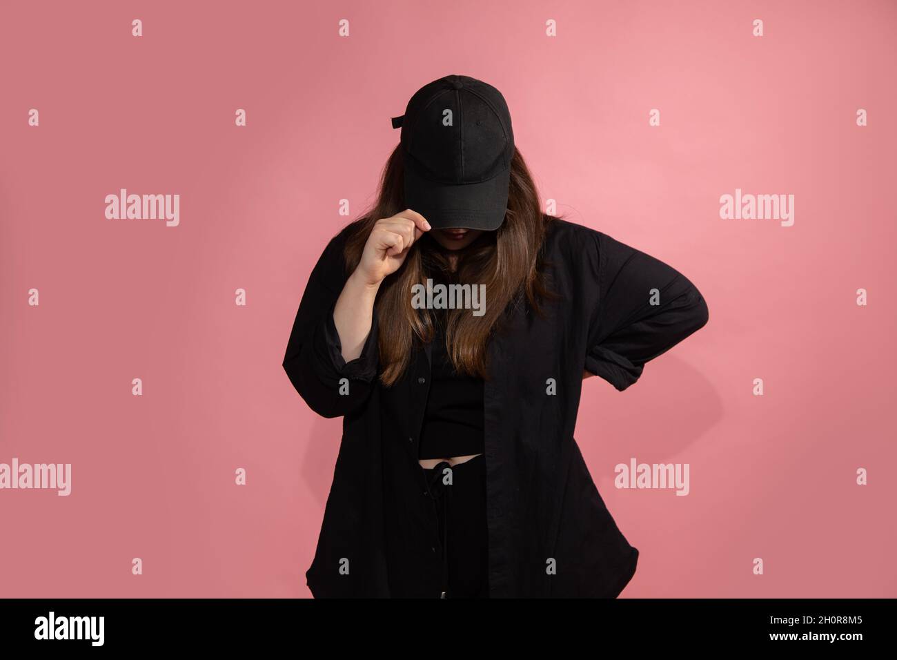 Mujer joven irreconocible con gorra negra de béisbol bajó la cabeza.  Simulación, espacio de copia. Sportswear, fondo rosa, foto de estudio  Fotografía de stock - Alamy