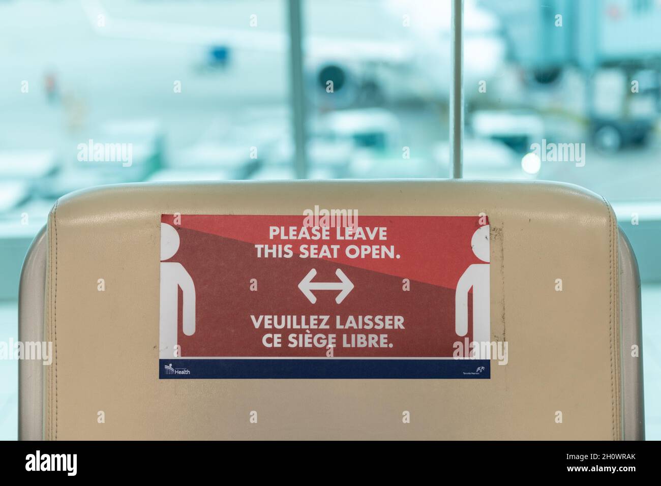 Signo de distanciamiento social durante la pandemia de Covid-19 en un asiento en el Aeropuerto Internacional de Person en la ciudad de Toronto, Canadá, año 2021 Foto de stock