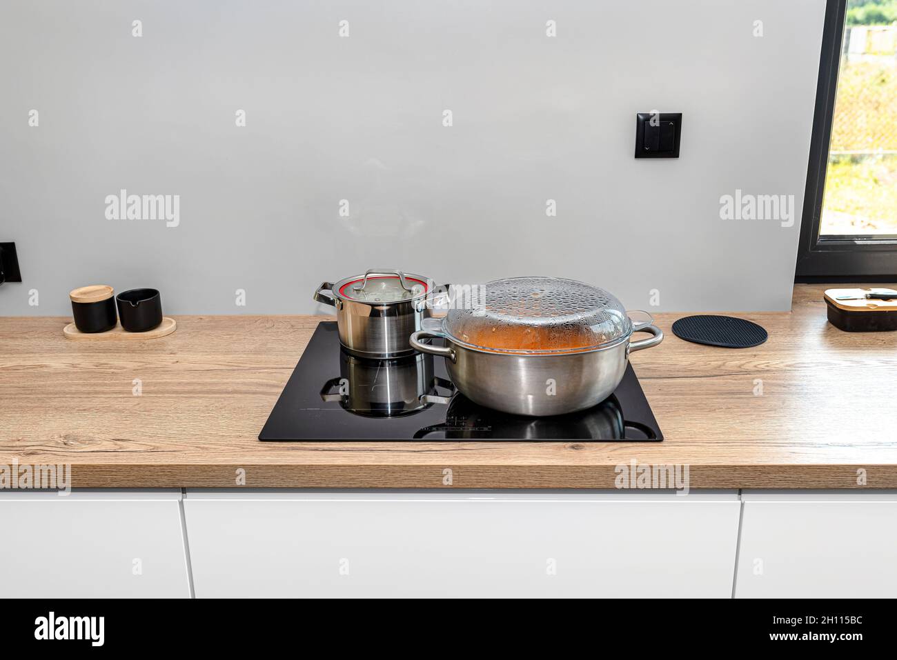 https://c8.alamy.com/compes/2h115bc/ollas-de-acero-con-un-plato-de-cocina-en-una-cocina-de-induccion-integrada-en-la-encimera-de-la-cocina-en-los-armarios-2h115bc.jpg