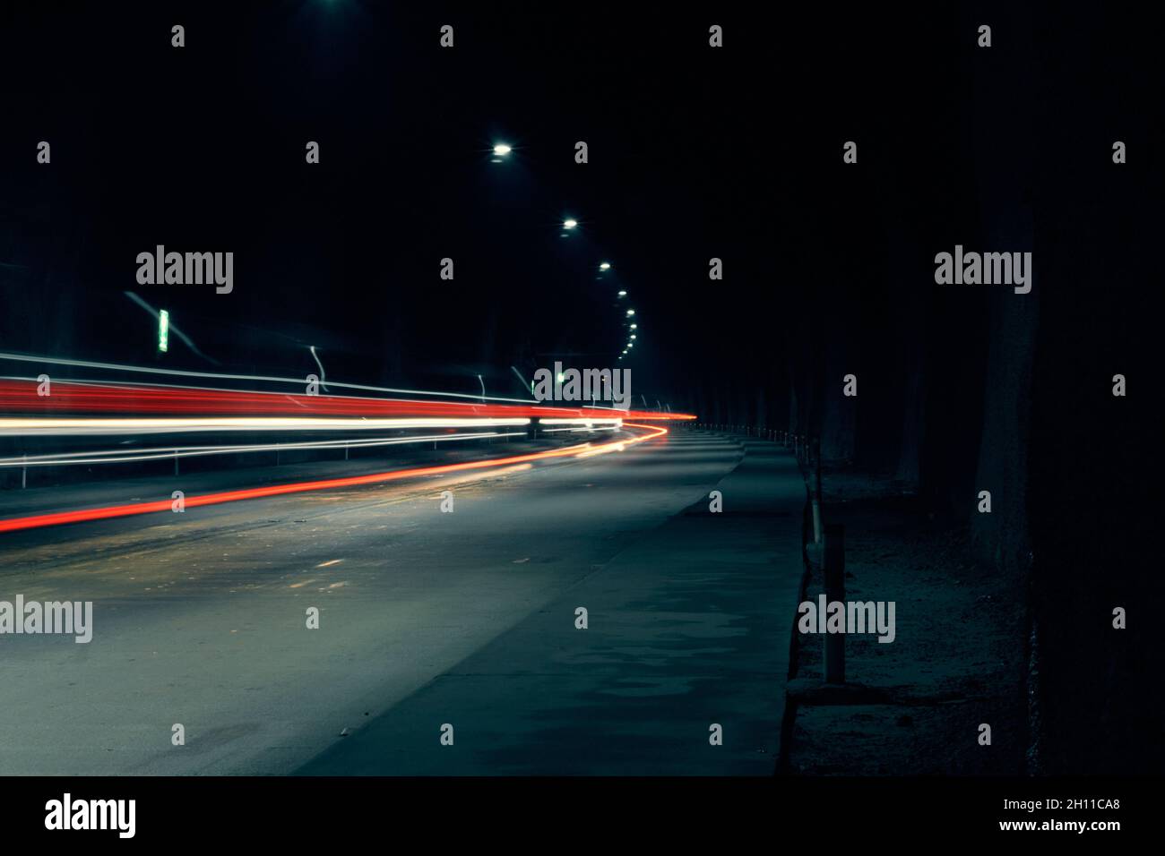 Túnel con brillantes senderos abstractos de semáforo por la noche, fondo horizontal Foto de stock