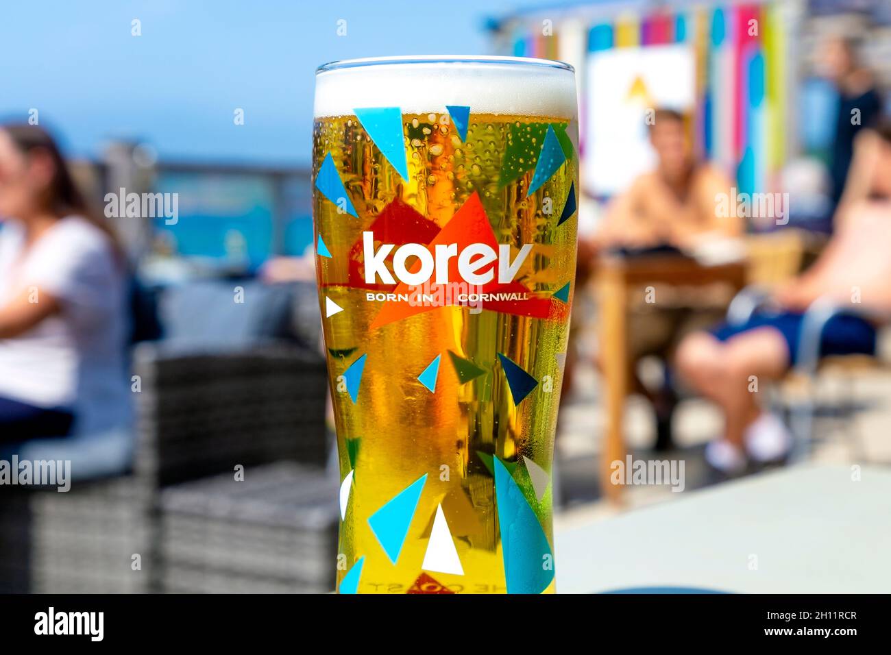 Cerveza Cornualles Korev en una copa en el Surf Beach Bar, Sennen Cove, Penwith Penwith Peninsula, Cornwall, Reino Unido Foto de stock