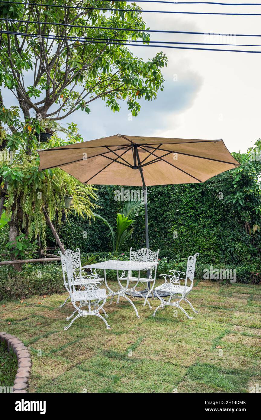 Juego de mesa blanca con sillas y sombrilla en el jardín en el patio  trasero Fotografía de stock - Alamy