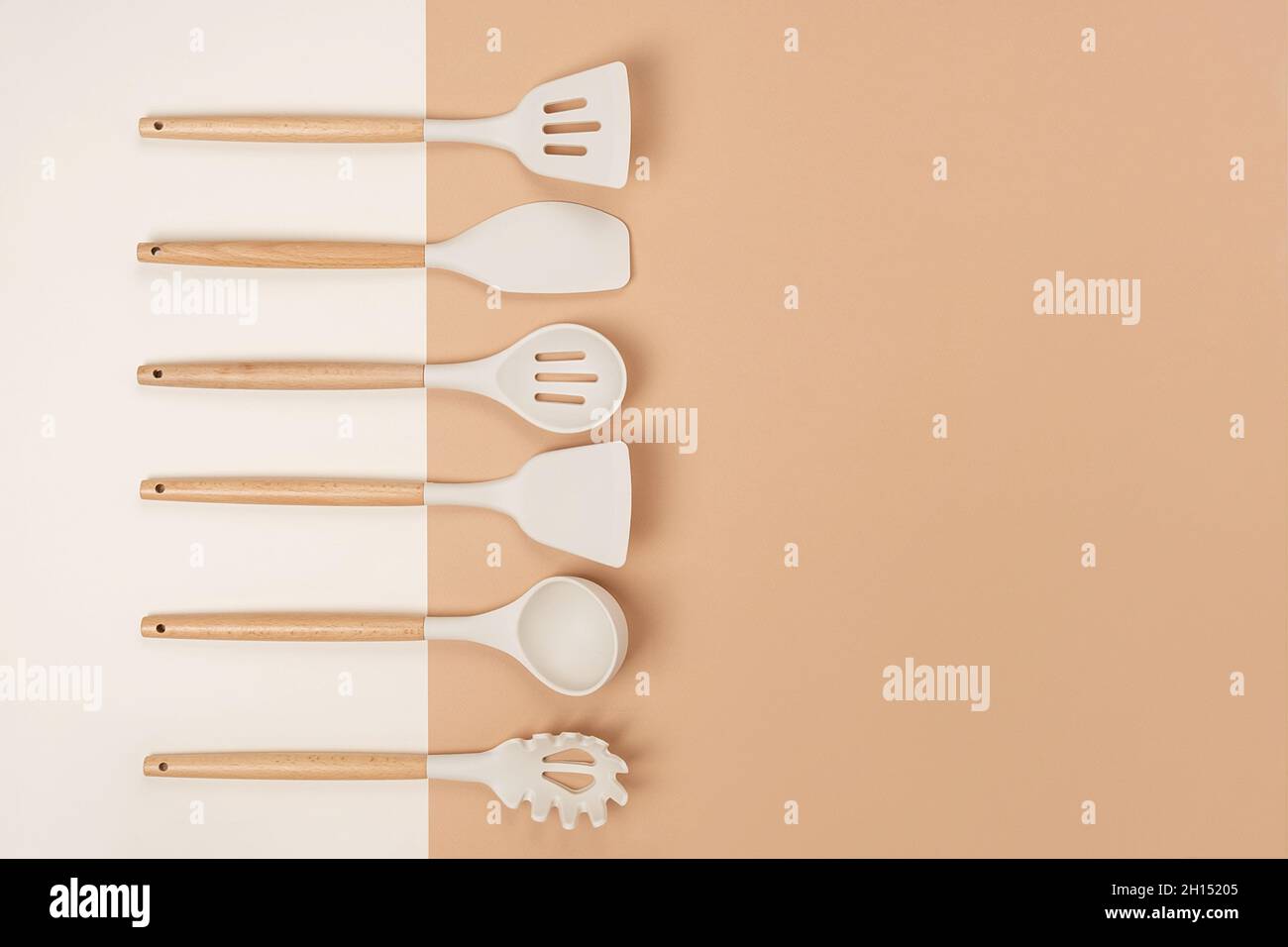 Juego de utensilios de cocina. Herramientas de cocina de silicona con mango de madera sobre fondo beige con espacio de copia. Vista superior Lay plano. Foto de stock