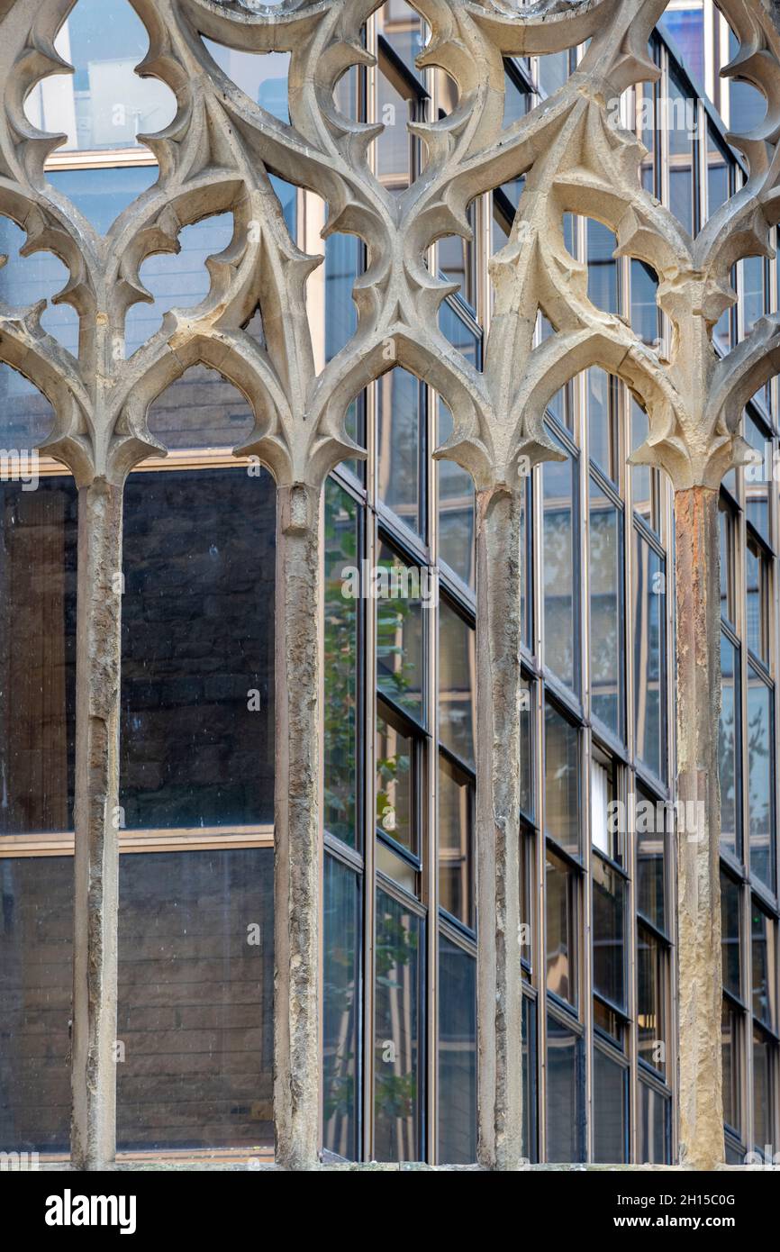 estilos arquitectónicos medievales y contemporáneos que contrastan con una histórica ventana de piedra con las modernas oficinas o apartamentos acristalados Foto de stock