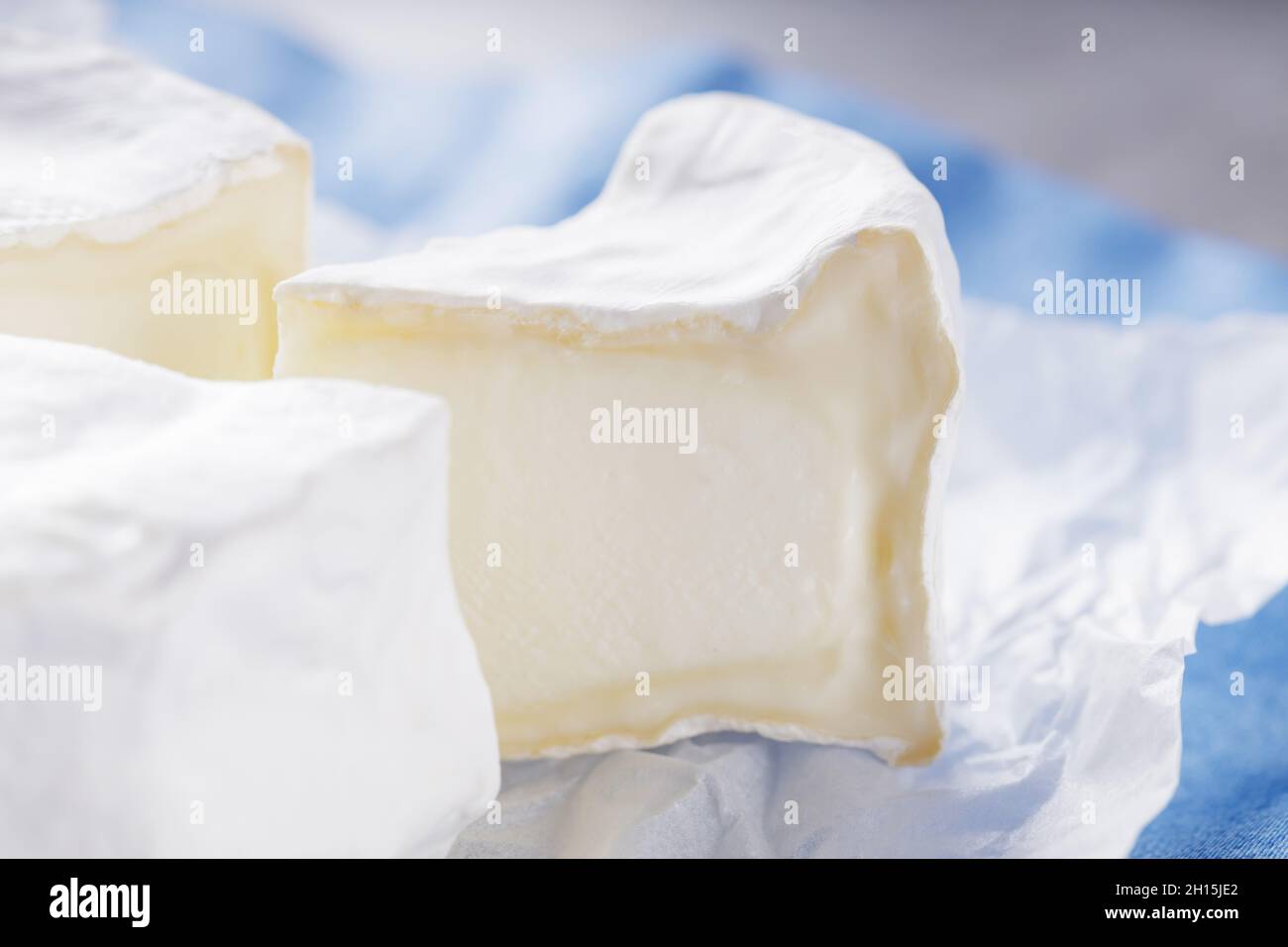 Queso Camembert sobre servilleta azul. Queso blanco sobre la superficie de cemento. Espacio de copia Foto de stock