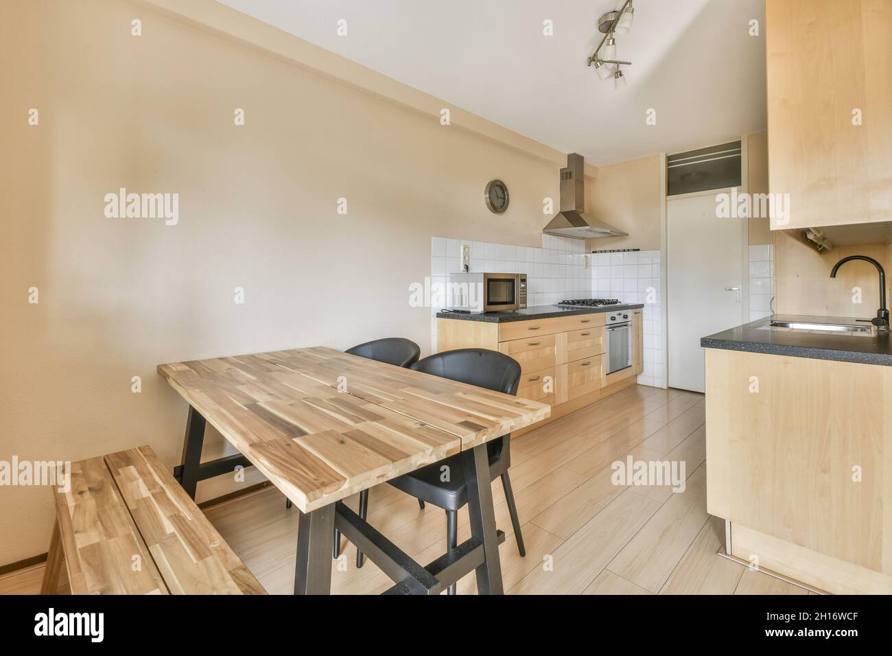 Interior de cocina moderna con paredes beige muebles de madera armarios  horno microondas estufa campana comedor mesa y sillas Fotografía de stock -  Alamy