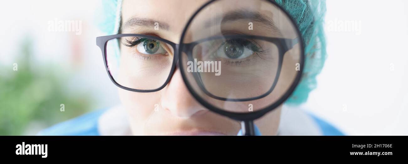 Retrato de una mujer doctora en gafas mira a través de una lupa Fotografía  de stock - Alamy