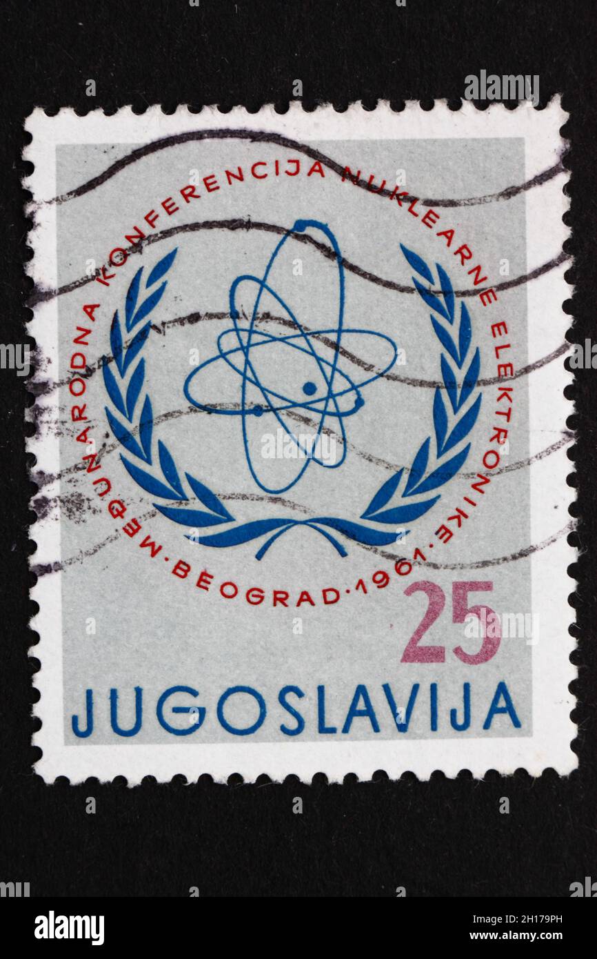 YUGOSLAVIA - CIRCA 1961: Un sello impreso en Yugoslavia muestra el emblema de la Comisión Atómica Internacional, Conferencia Electrónica Nuclear Internacional Foto de stock