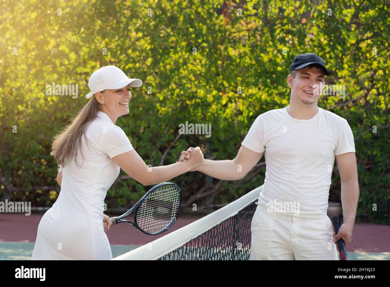 apretón de manos después de un partido de tenis, un joven blanco y una mujer. hermano y hermana jugaban un partido de tenis. Foto de stock