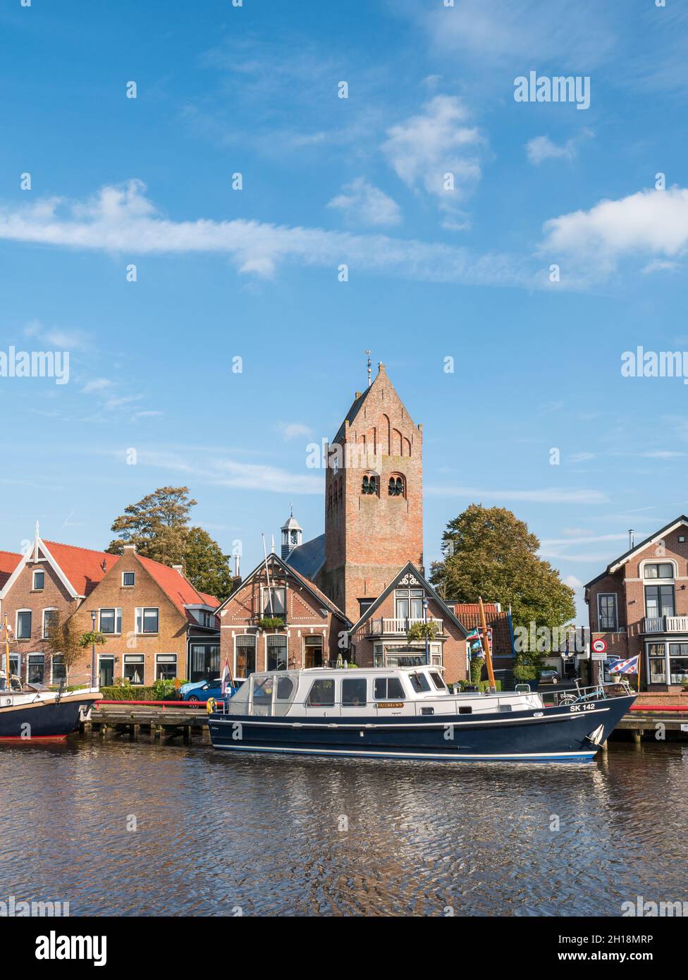 Barcos, casas y torre de la iglesia en el casco antiguo de Grouw, Friesland, Países Bajos Foto de stock